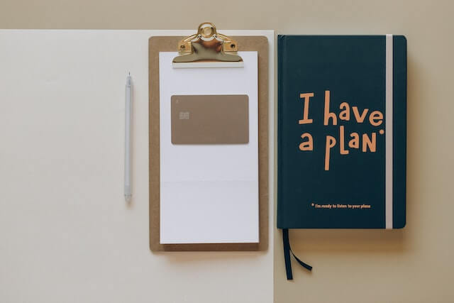 "Financial Advisor Diary that says 'I have a Plan' on a Desk along with a clipboard "